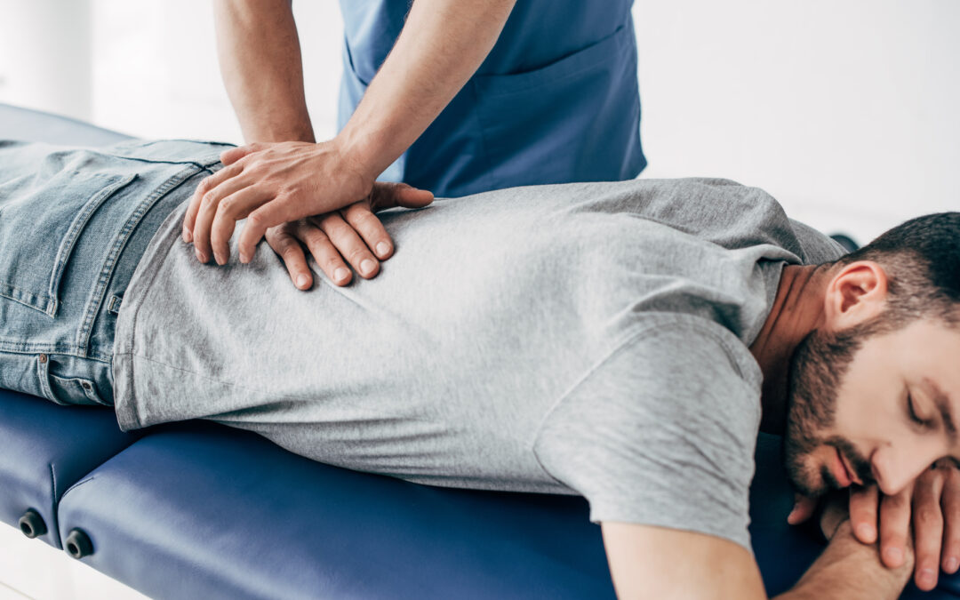 chiropractor massaging back of man on Massage Table in hospital