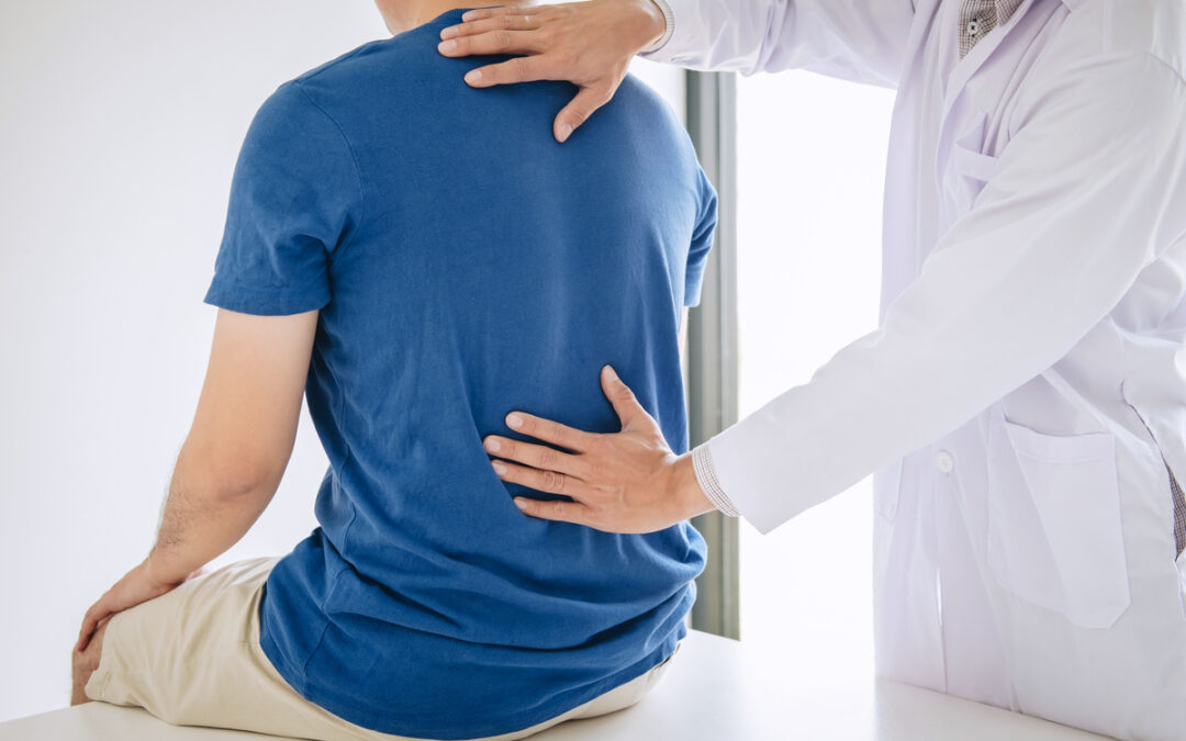 chiropractor treating lower back pain patient after while giving exercising treatment on stretching in the clinic